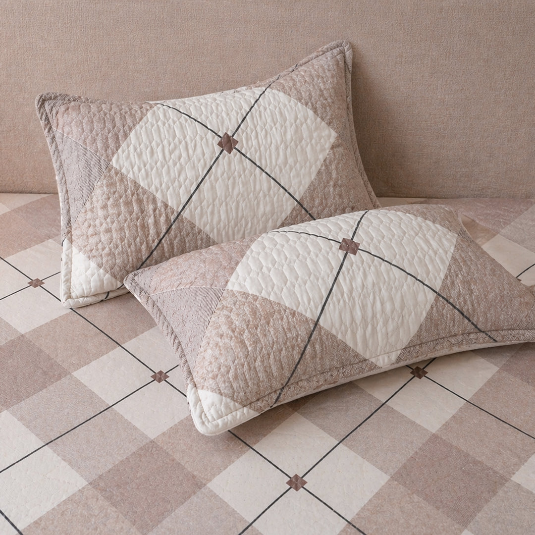 Two quilted pillow cover with king size bedsheet with geometric pattern on a checkered floor.